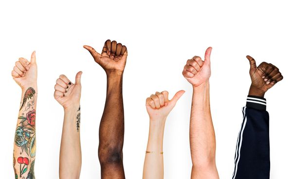 Arms in the air with thumbs up with different skin colours and one with tattoos to show diversity