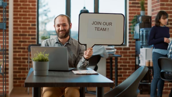 Cheerful man smiling and holding a Join our Team sign